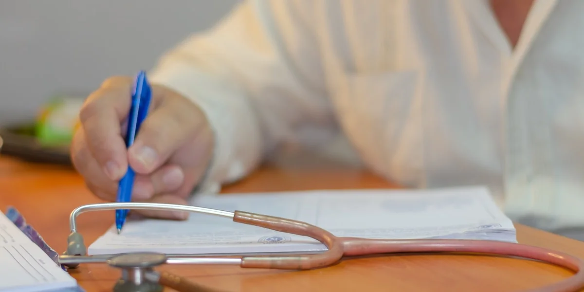 a person writing on a piece of paper with a stethoscope
