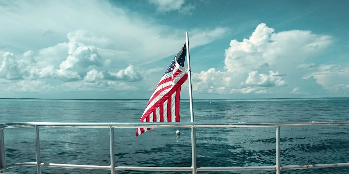 red white and blue flag on white metal pole near sea during daytime