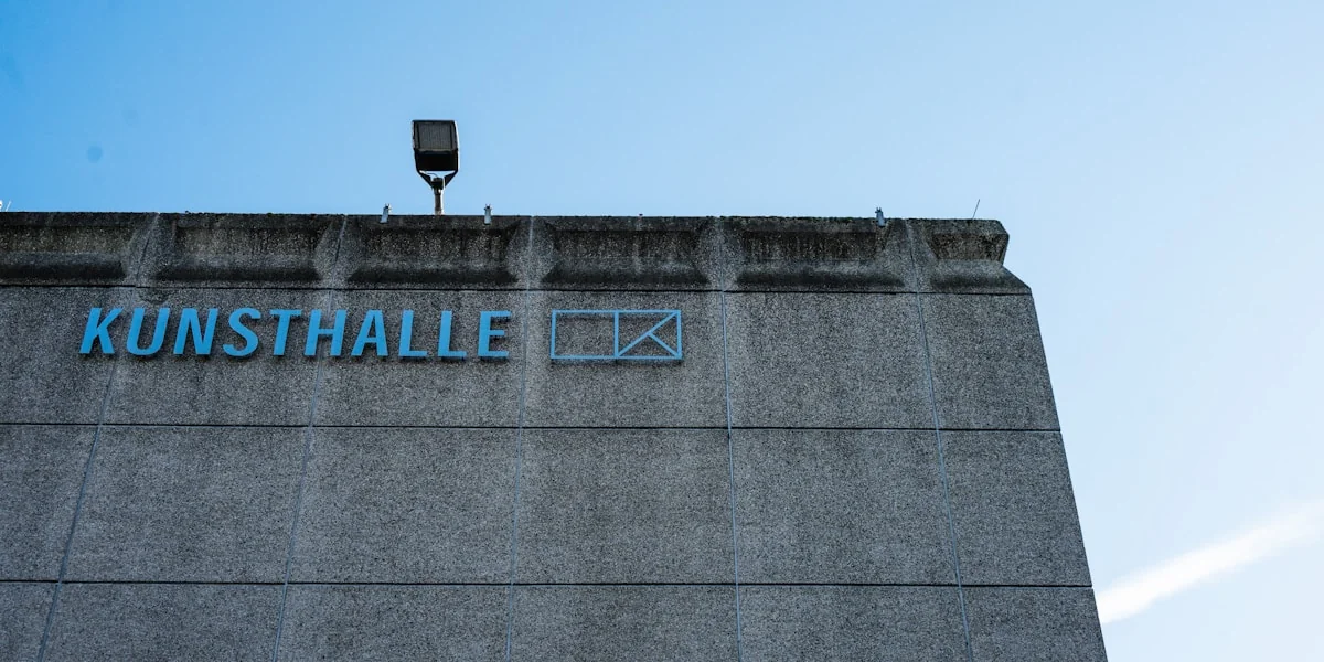 Concrete building with 'kunsthalle' sign under blue sky.
