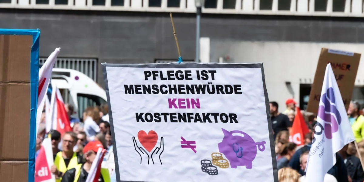 Protest sign: care is human dignity, not a cost factor.