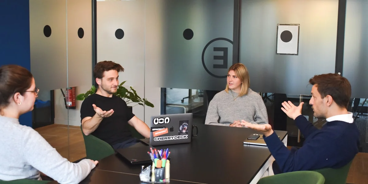 Four people in a meeting around a black table in a modern office