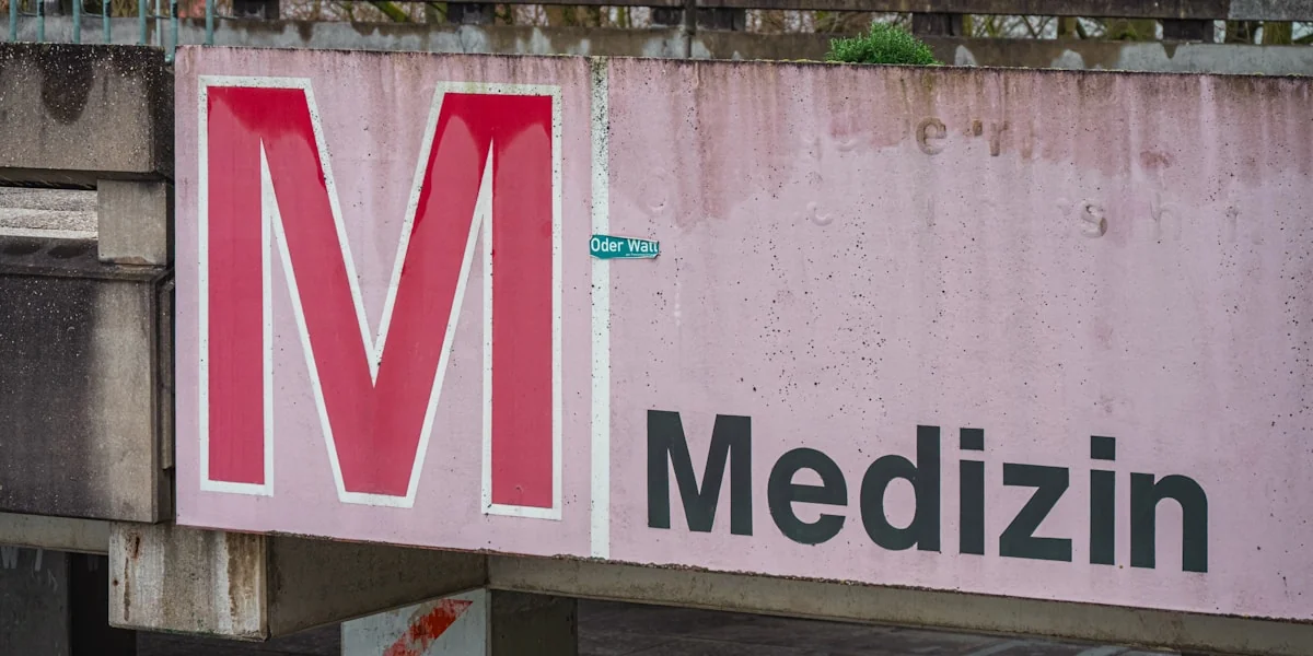 Large red m and "medizin" sign on concrete structure.