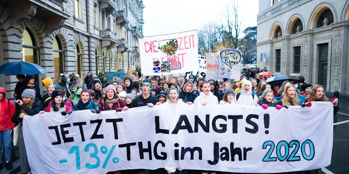 people holding banner on road between buildings during daytime
