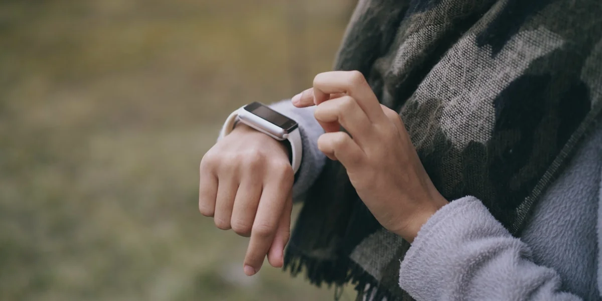 Person checking a smartwatch outdoors with a scarf