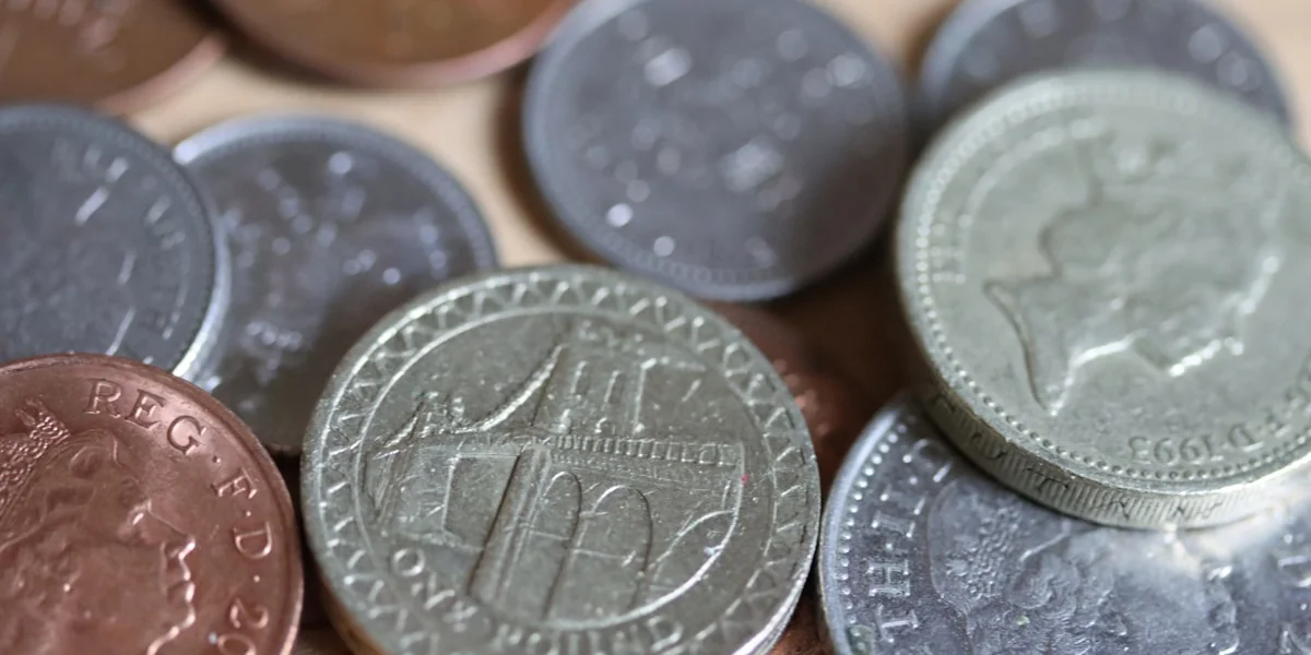 a pile of british coins sitting on top of a wooden table