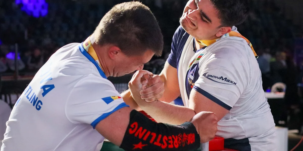 Two men intensely arm wrestling at a competitive event.