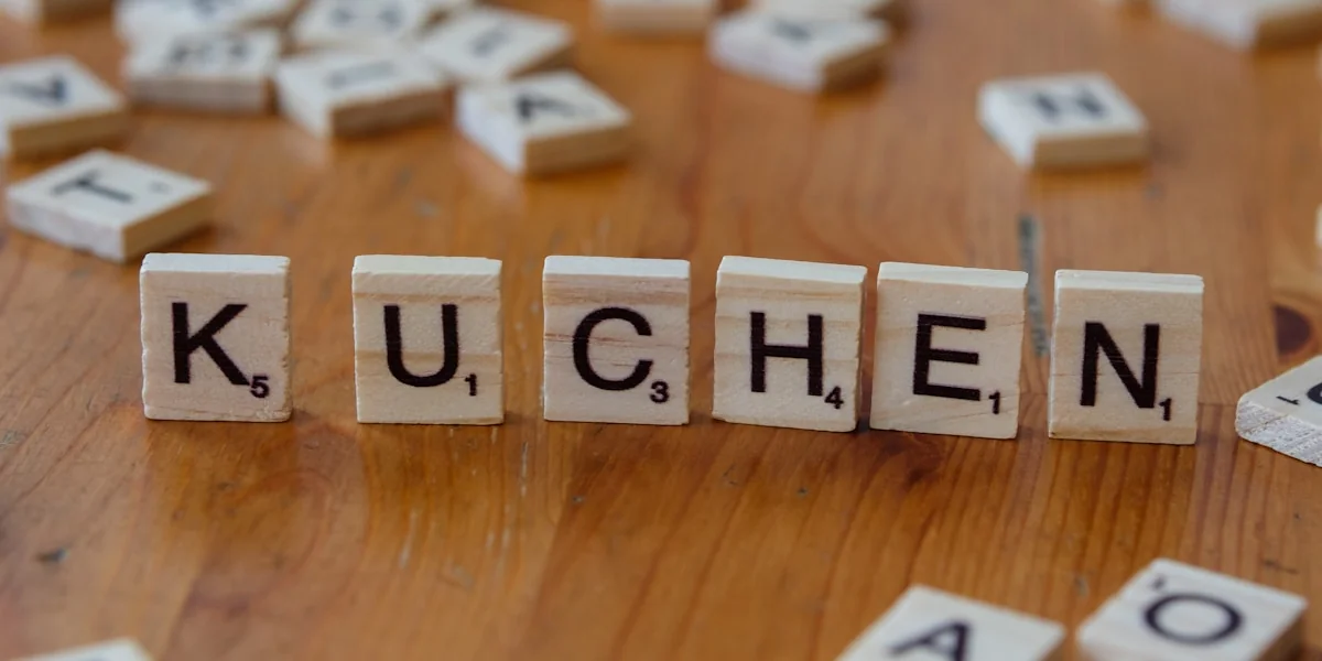 A wooden table topped with scrabble tiles that spell out the word kuchen