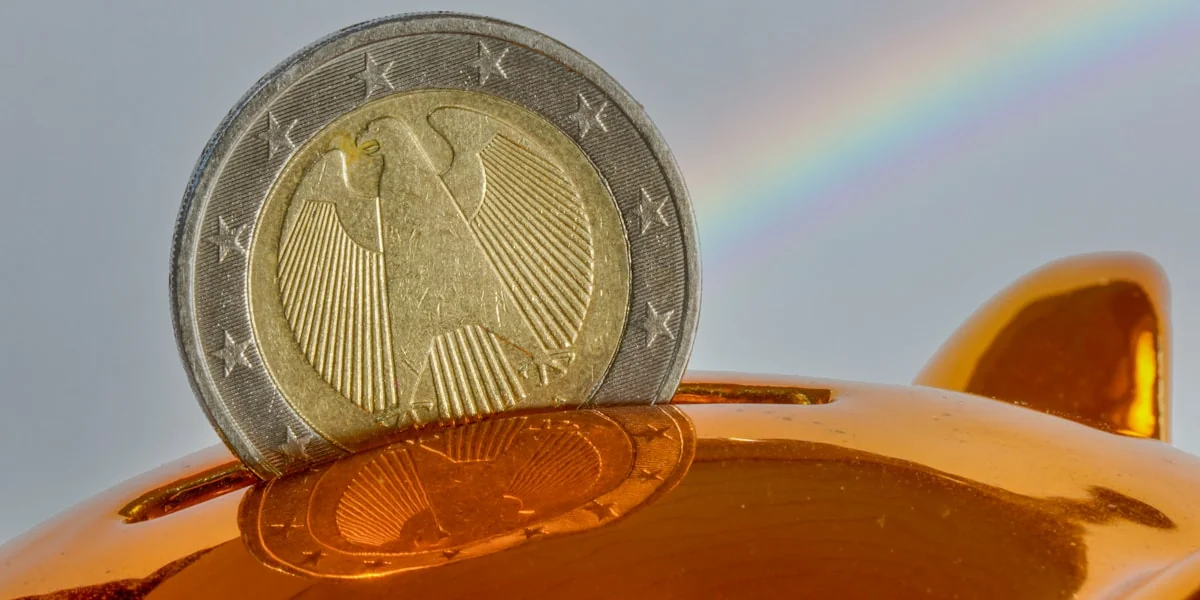 A coin being placed into a golden piggy bank.