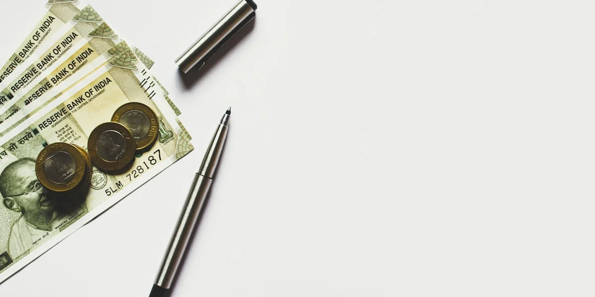 gray pen beside coins on Indian rupee banknotes