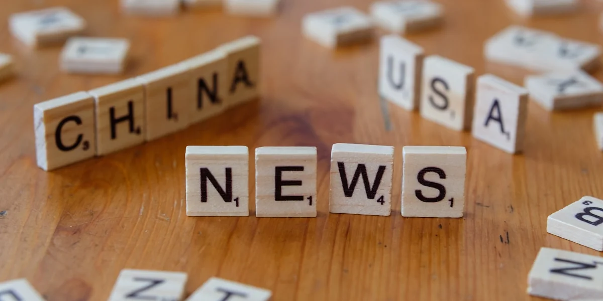 A wooden table topped with scrabble tiles spelling china news