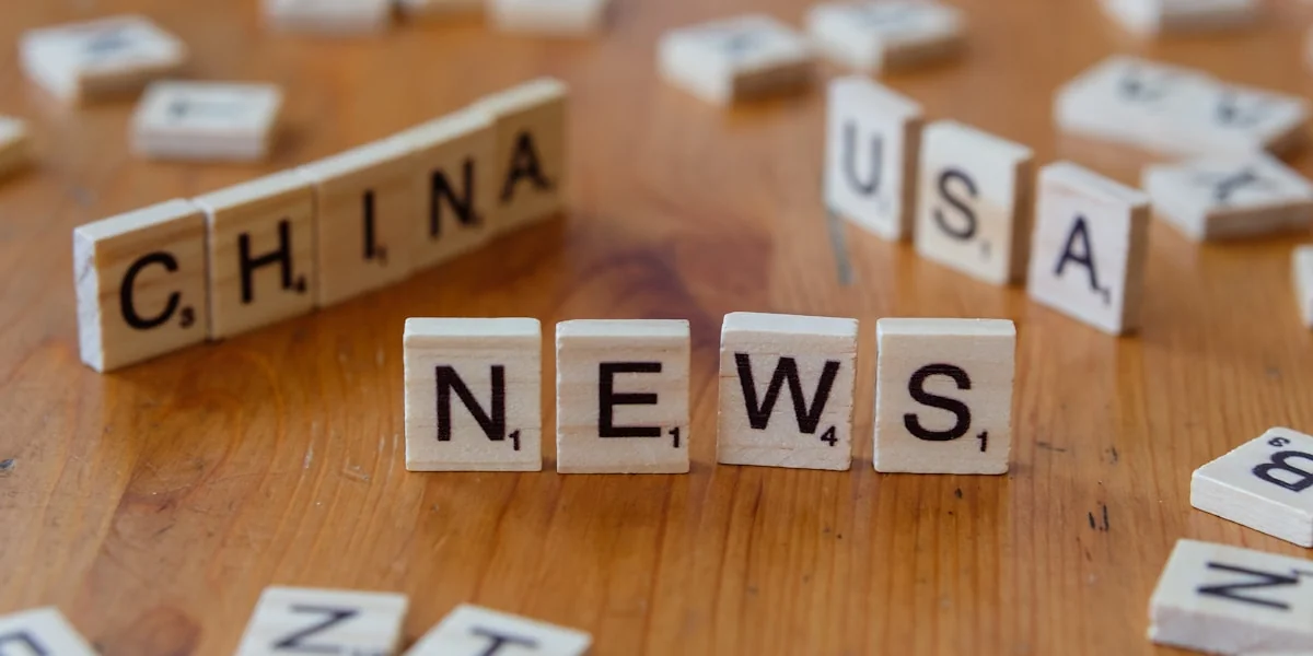 A wooden table topped with scrabble tiles spelling china news