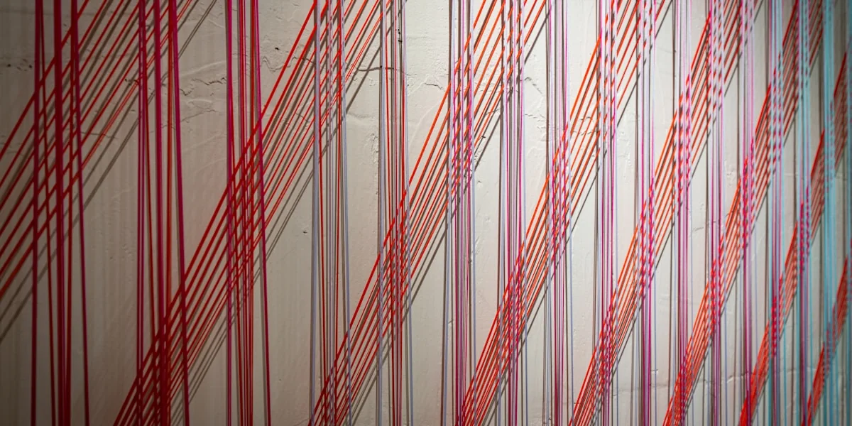 Red threads creating a striped pattern on a wall
