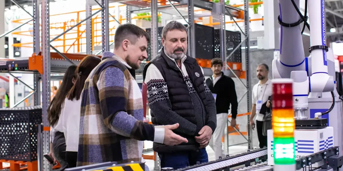Men observe automated conveyor belt system in warehouse