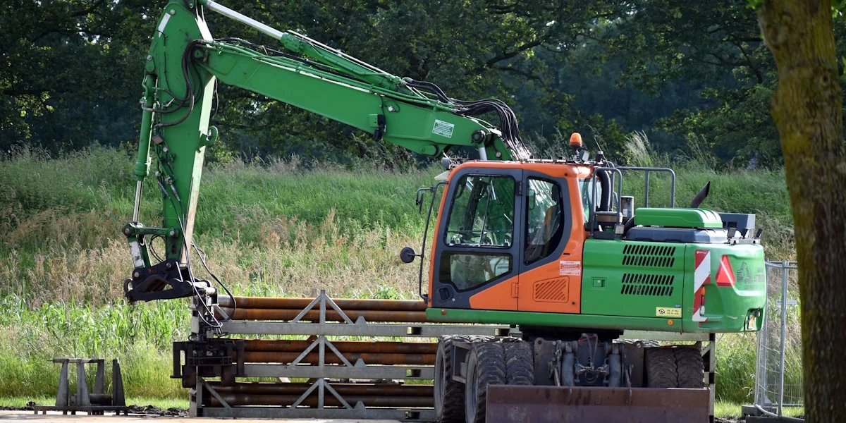 A green and orange truck parked next to a forest
