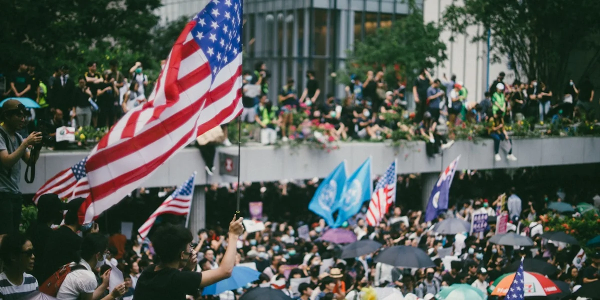 a crowd of people holding american flags and umbrellas