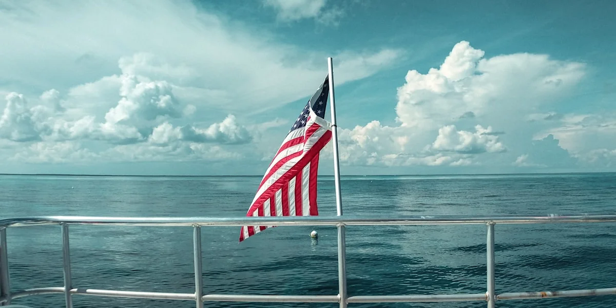 red white and blue flag on white metal pole near sea during daytime